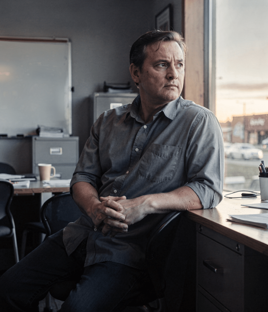 Concerned Alberta small business owner sitting at his office desk, looking out the window while weighing his company's technology decisions"